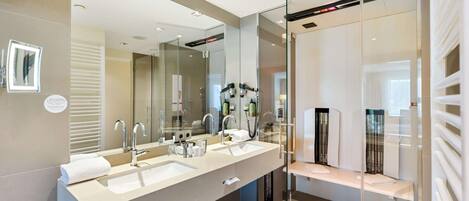A modern bathroom with two sinks, a large mirror, and a glass shower enclosure.