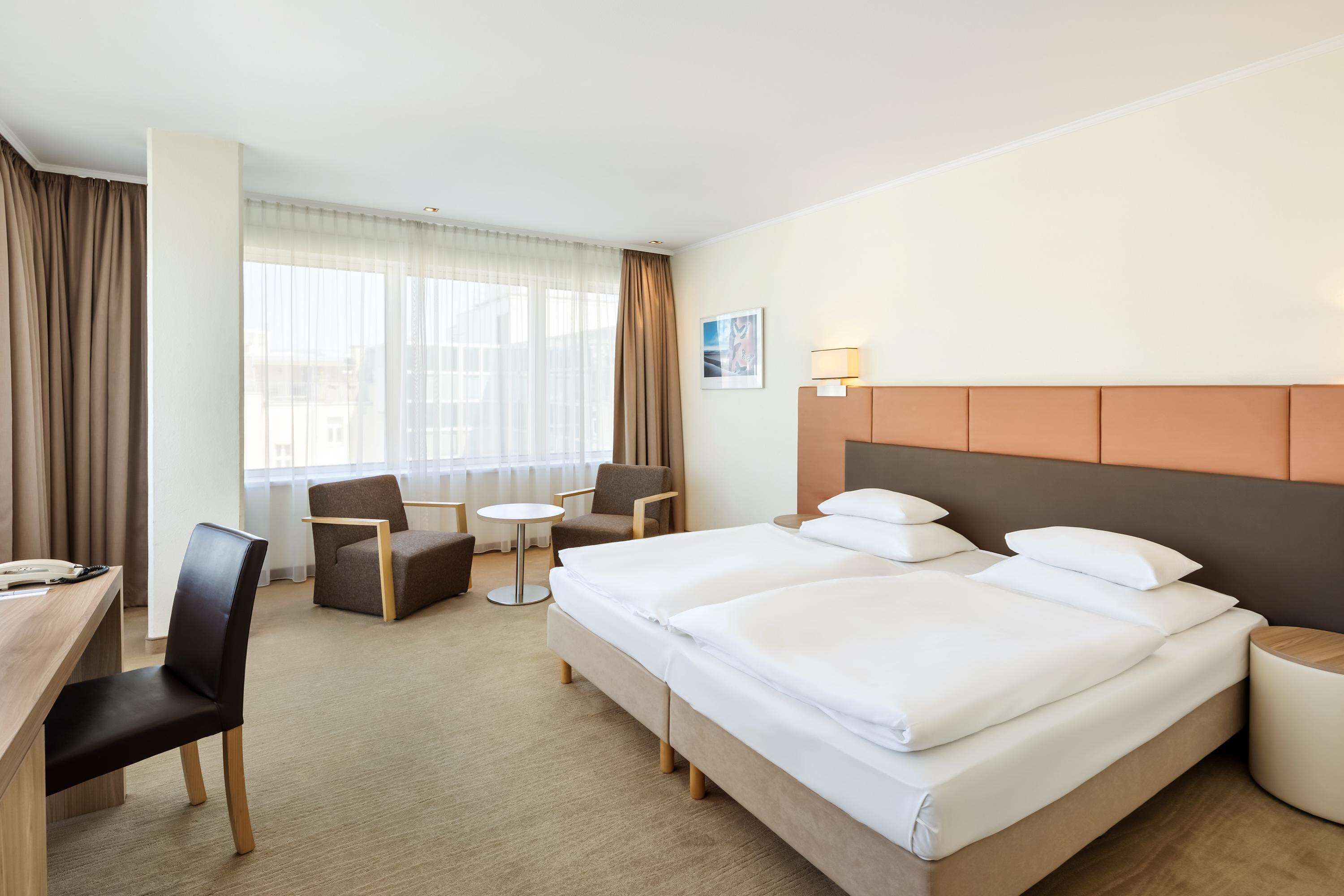 Una habitación de hotel con una cama grande, dos sillones, un escritorio y una mesita.