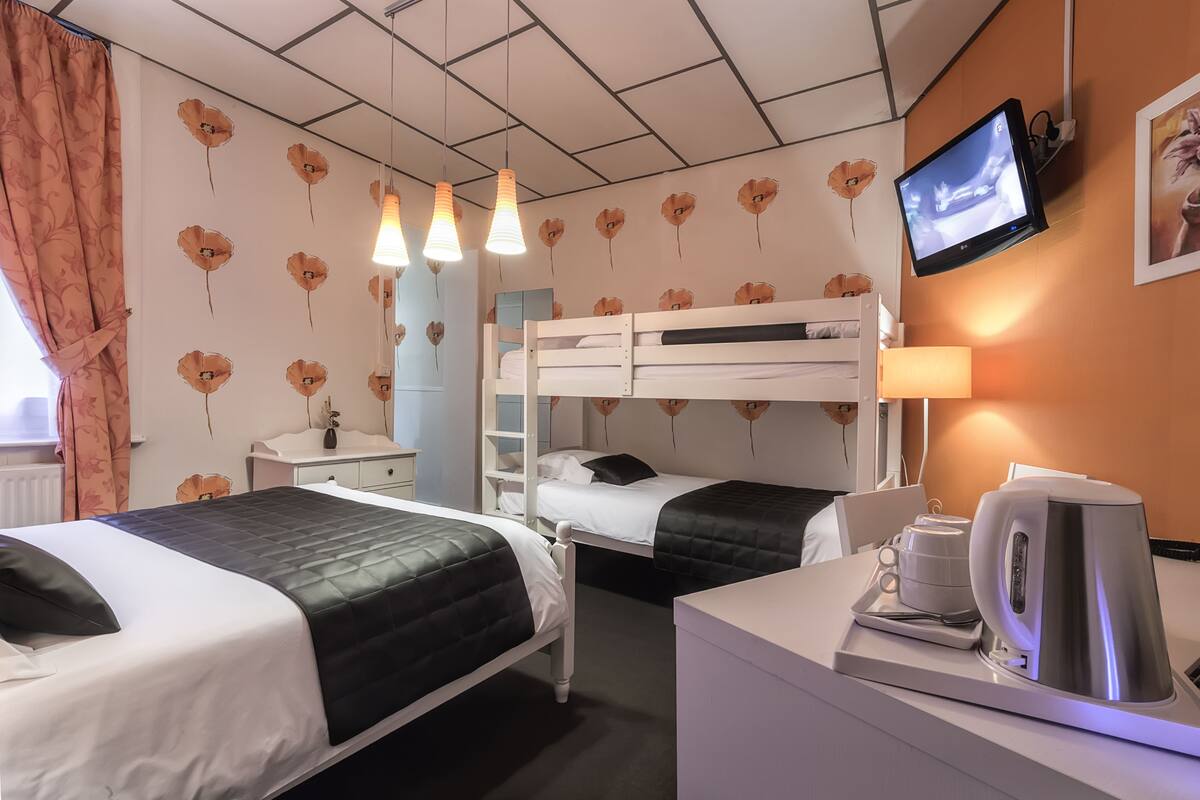 Ein Hotelzimmer mit zwei Betten, einem Fernseher, einer Kaffeemaschine und einem Schreibtisch mit einer Lampe.