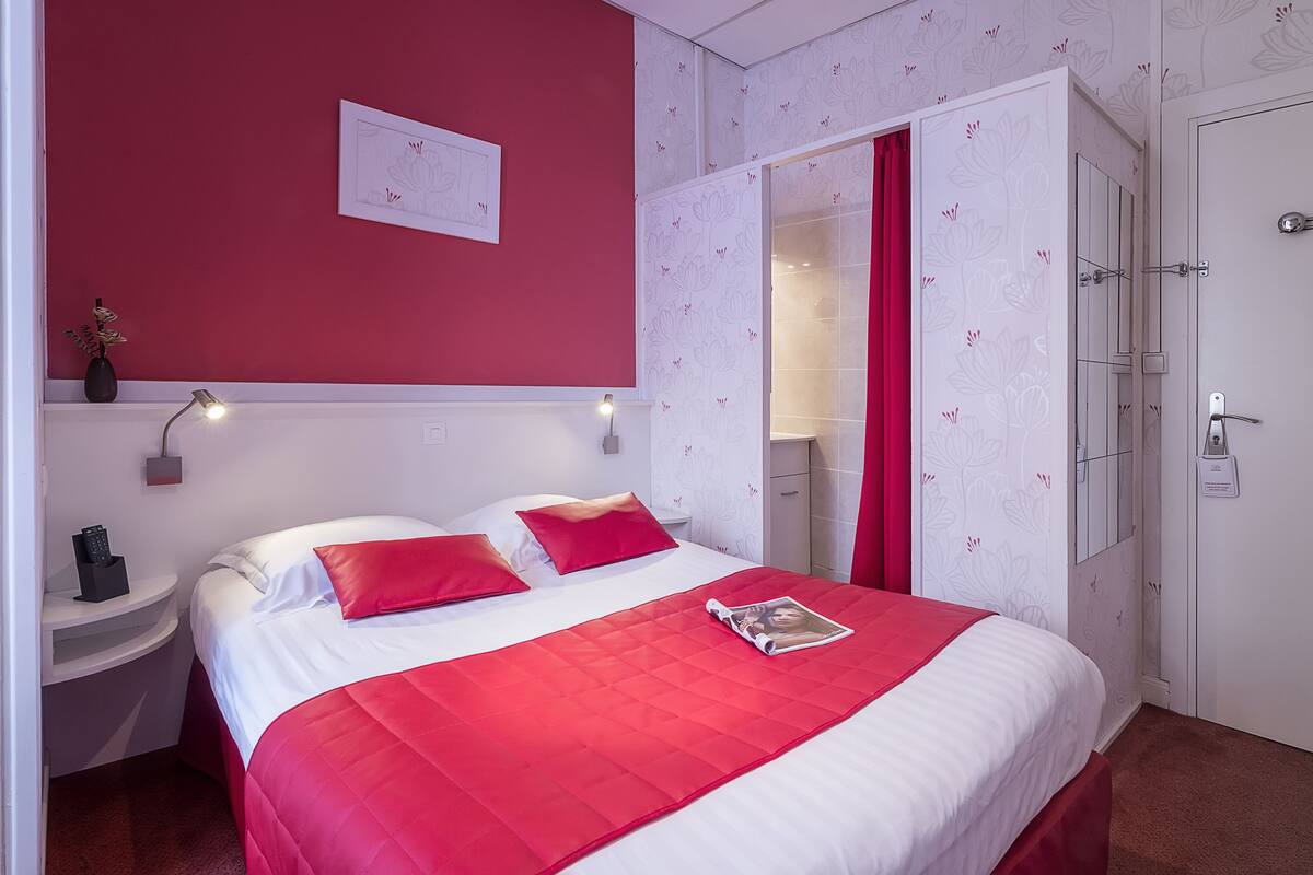 Ein Hotelzimmer mit Bett, Nachttisch, Spiegel und Kleiderschrank.