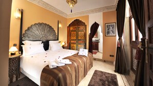 A hotel room with a large bed, ornate headboard, and a decorative door. - Riad Belle Époque (Marrakech)