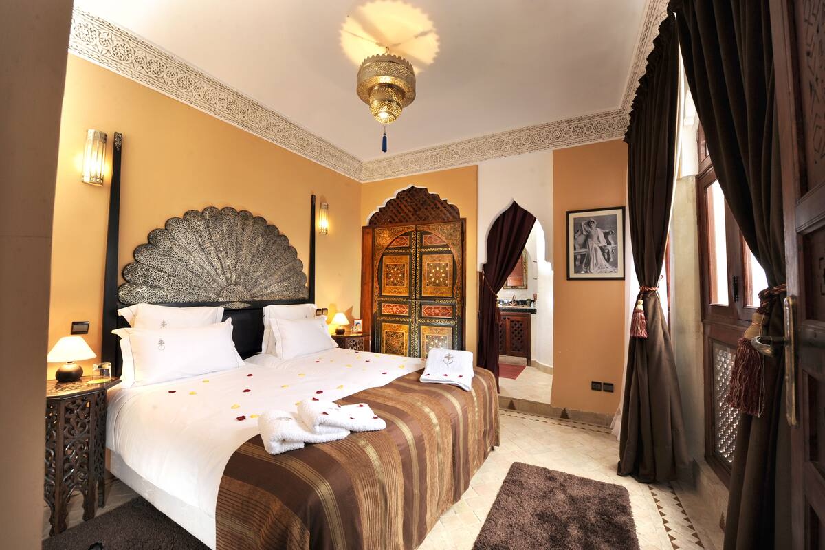 Una habitación de hotel con una cama grande, un cabecero ornamentado y una puerta decorativa.