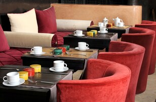 Un rincón acogedor con sillones tapizados de rojo, mesas de madera y un sofá con cojines rojos.