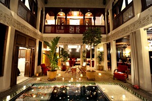 Una hall con piscina centrale, piante in vaso e zone relax.