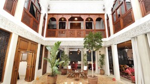 A courtyard with a central seating area, potted plants, and a tiled floor. - Riad Belle Époque (Marrakech)