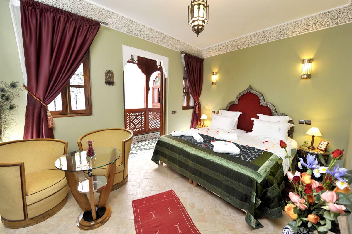 Una habitación de hotel con una cama, una silla, una mesita y objetos decorativos.