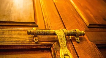 Un maniglia in ottone con decorazioni elaborate su una porta di legno.