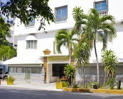 Un edificio blanco con un letrero de restaurante, palmeras y una estatua al frente.