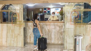 Uma área de recepção de hotel com balcão de mármore e um recepcionista.