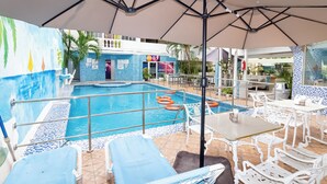 A pool area with lounge chairs, a table, and umbrellas. - La Casona Dorada (Santo Domingo)