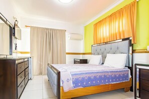 Une chambre à coucher comprenant un lit, une commode, un appareil de climatisation et une table de chevet.