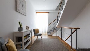 En modern inredning med en trappa, en soffa, ett sidobord med en växt och en bokhylla.