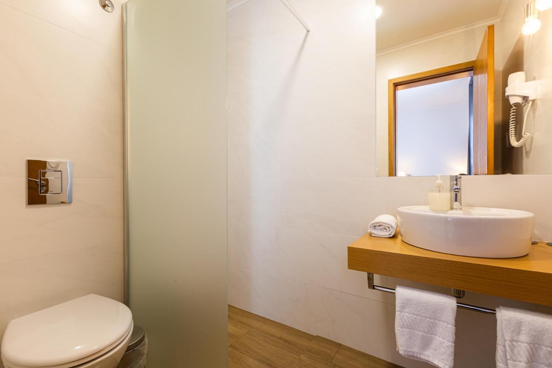 A modern bathroom with a toilet, a sink with a mirror above it, and a shower area.