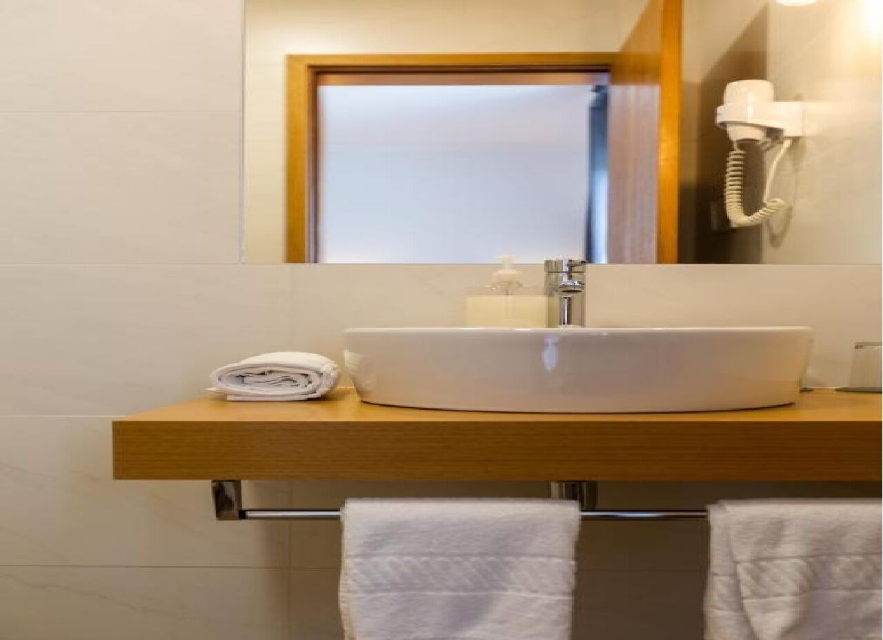 A bathroom with a white sink, a mirror, and a telephone.