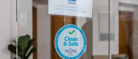 A glass door with a sign indicating mandatory mask use in common areas and a 'Clean & Safe' sticker.
