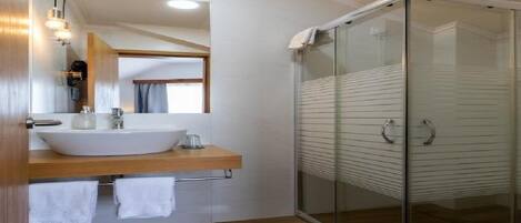 A modern bathroom with a large sink, mirror, and glass shower enclosure.