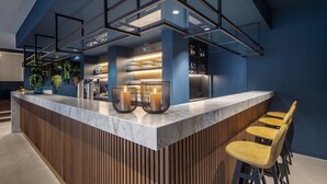 A modern bar area with a marble countertop, wooden slats, and bar stools.