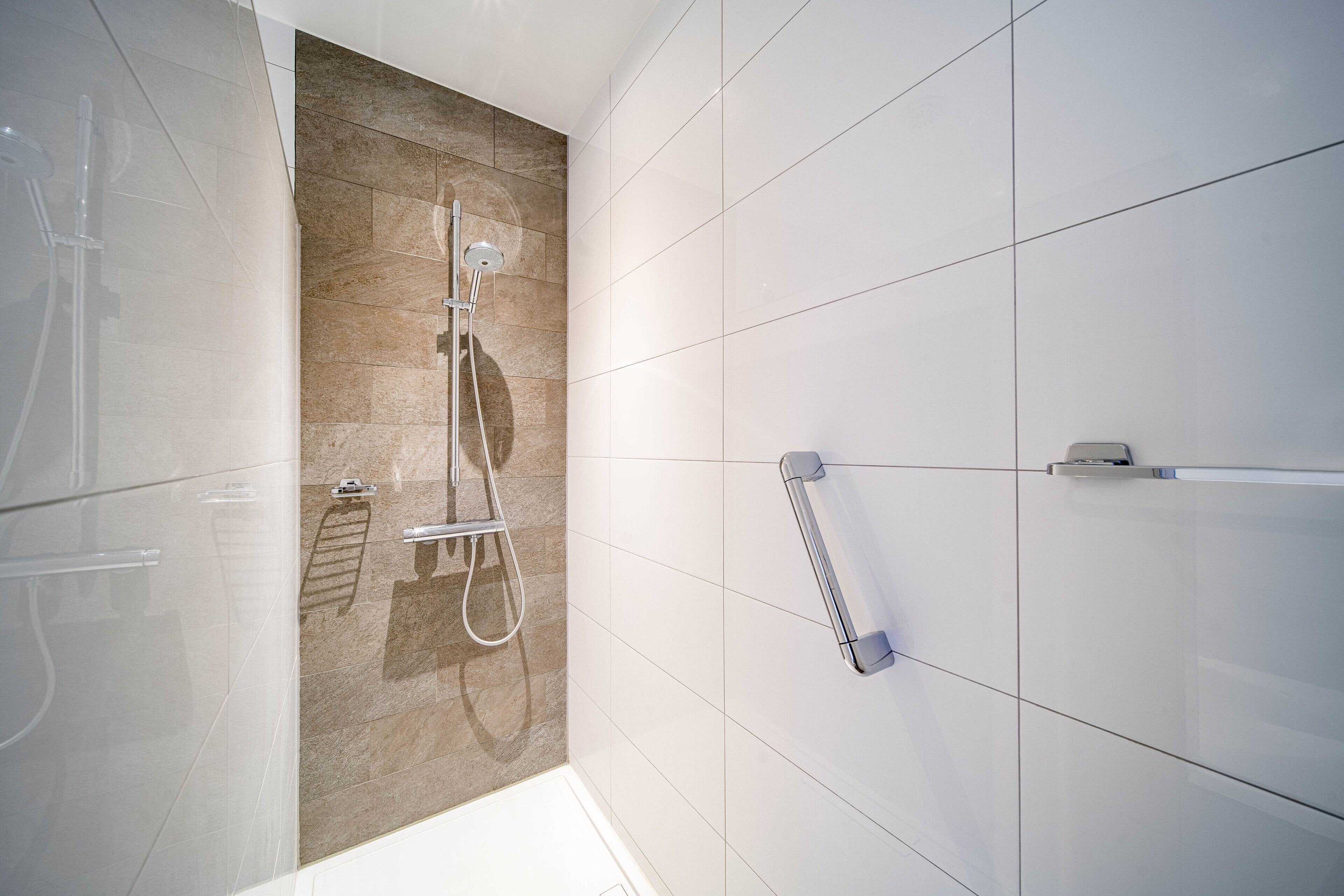 A modern bathroom with a shower, a towel rack, and a toilet.