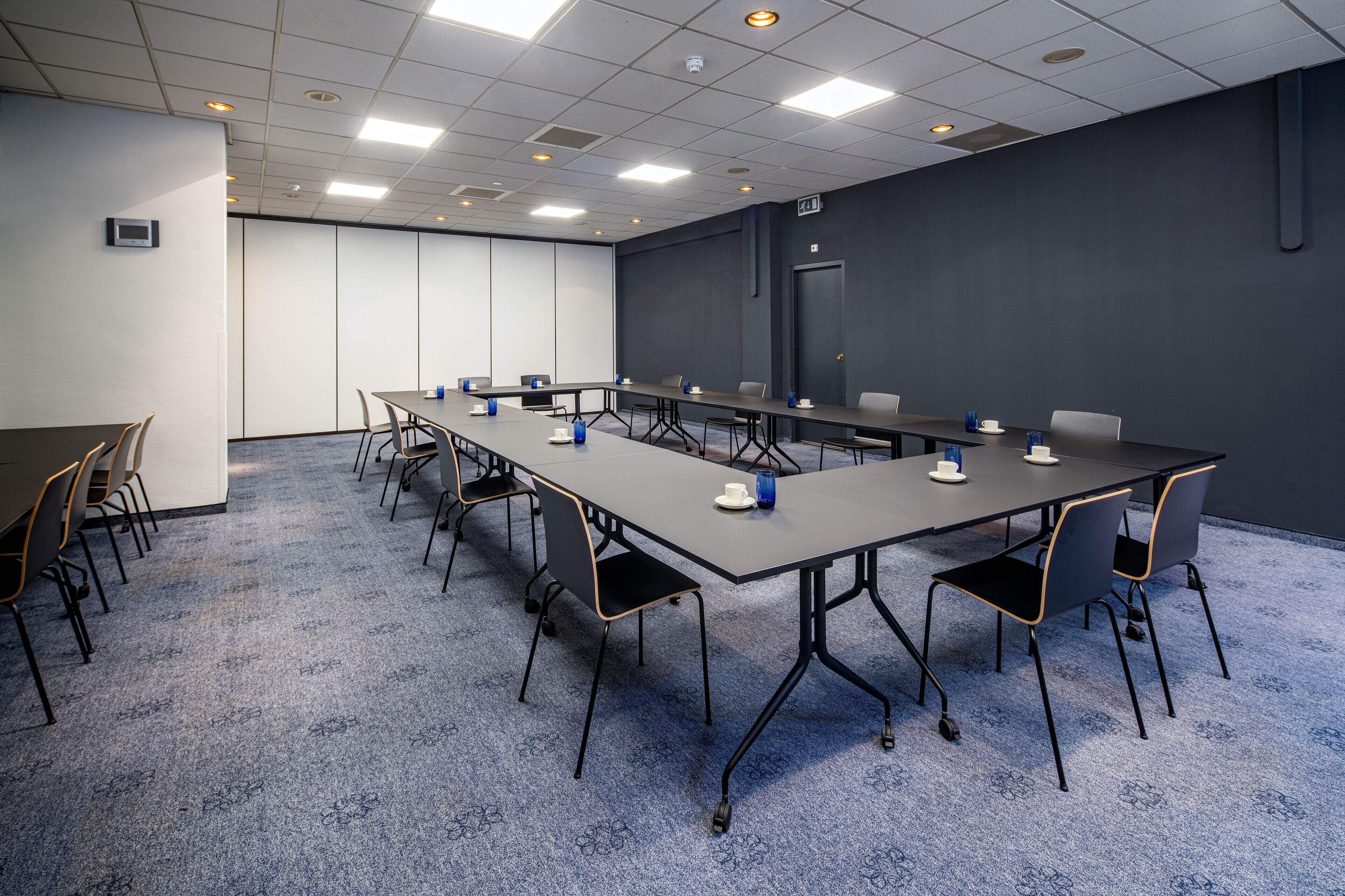 A conference room with a long table, chairs, and a carpeted floor.
