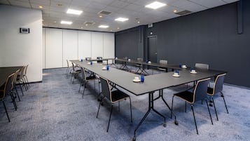 A conference room with a long table, chairs, and a carpeted floor.