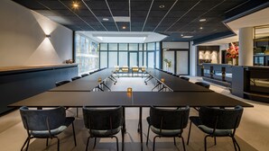 A conference room with a long table, four chairs, and a modern ceiling design.