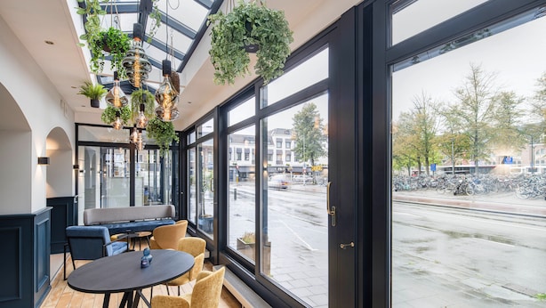 A modern interior with a seating area, large windows, and hanging plants.