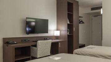 Ein Hotelzimmer mit Bett, Schreibtisch, Stuhl, Fernseher und Kleiderschrank.