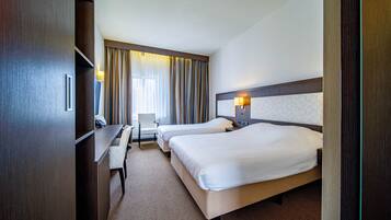 A hotel room with two beds, a desk, and a chair.