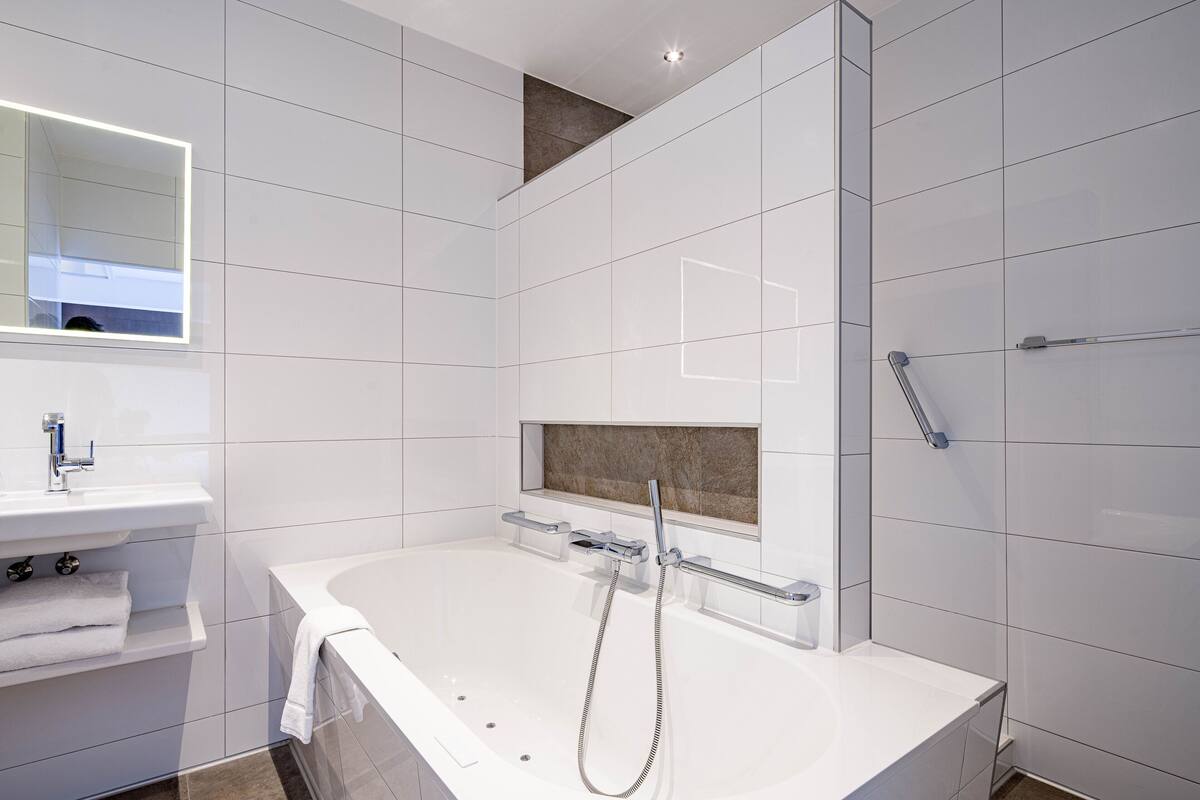 A modern bathroom with a large bathtub, a separate shower area, and a vanity with a mirror.