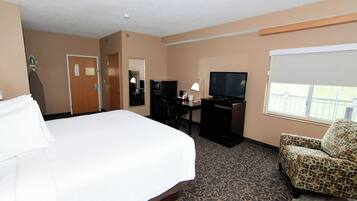 Quarto de hotel com uma cama grande, uma escrivaninha com computador, televisão e uma cadeira.