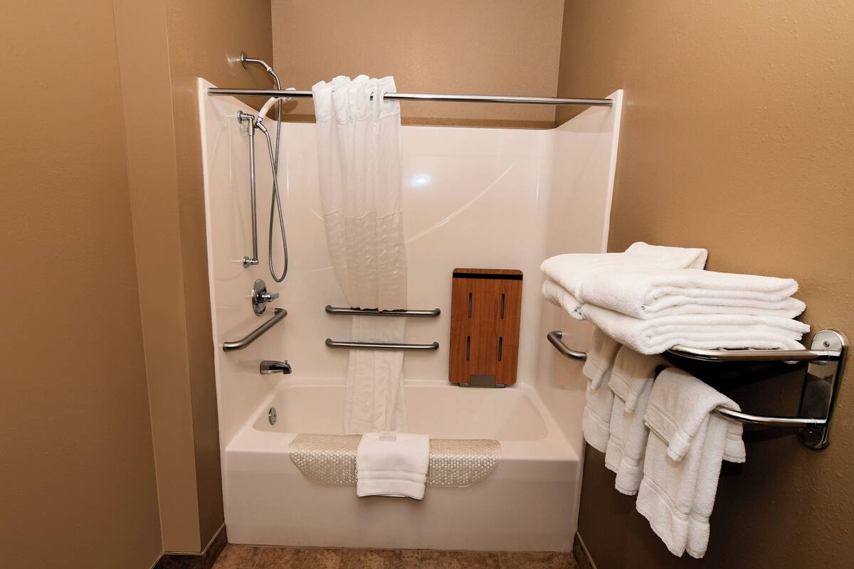 A modern bathroom with a bathtub, shower, and towel rack.