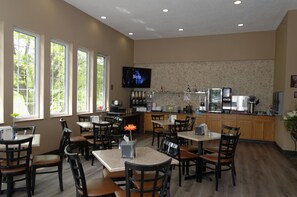 A restaurant with a kitchen area, dining tables, chairs, and a television. - Cobblestone Inn & Suites - Denison Majestic Hills (Denison)