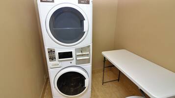 A stacked washer and dryer unit with a table beside it.