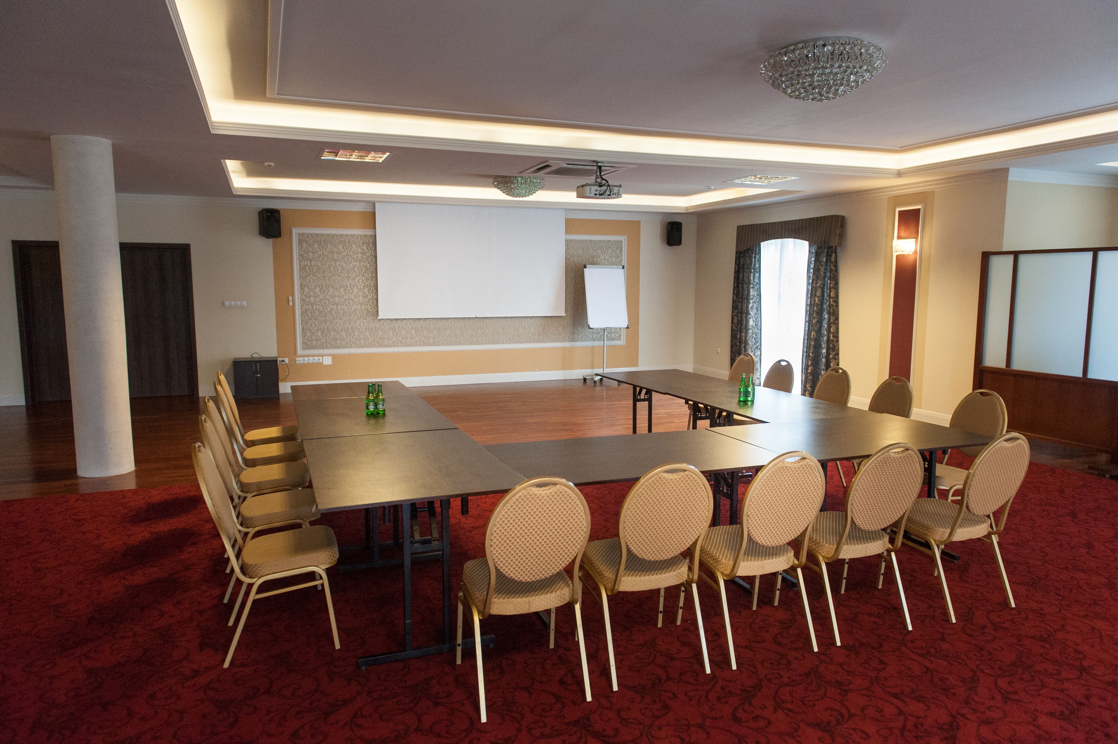 Uma sala de conferências com uma mesa comprida, cadeiras, um projetor e uma tela.