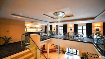 A hotel lobby with a central staircase, seating areas, and a chandelier.