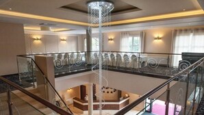 Un amplio vestíbulo de hotel con una zona de estar central, un mostrador de recepción y una barandilla de cristal que da al vestíbulo.