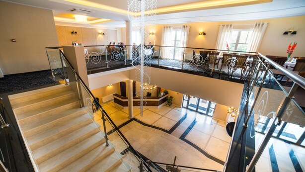 Un hall de hotel con una zona de estar central, una escalera y una barandilla de cristal.