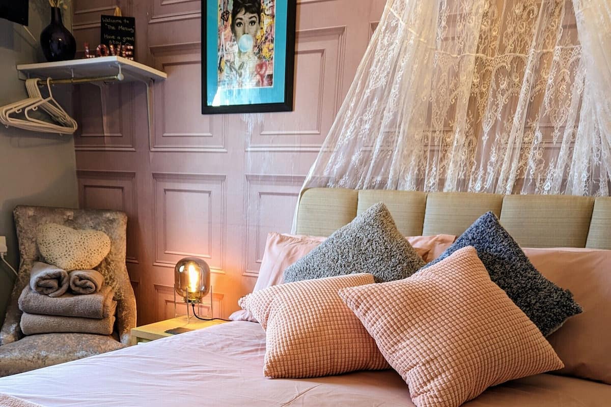 A neatly made bed with a textured blanket, a canopy, and several pillows.