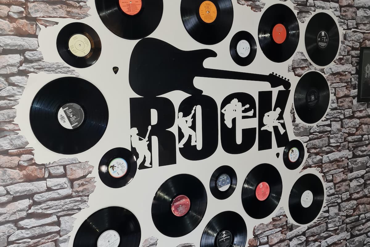 A wall with a rock-themed design featuring vinyl records and a silhouette of a guitar.
