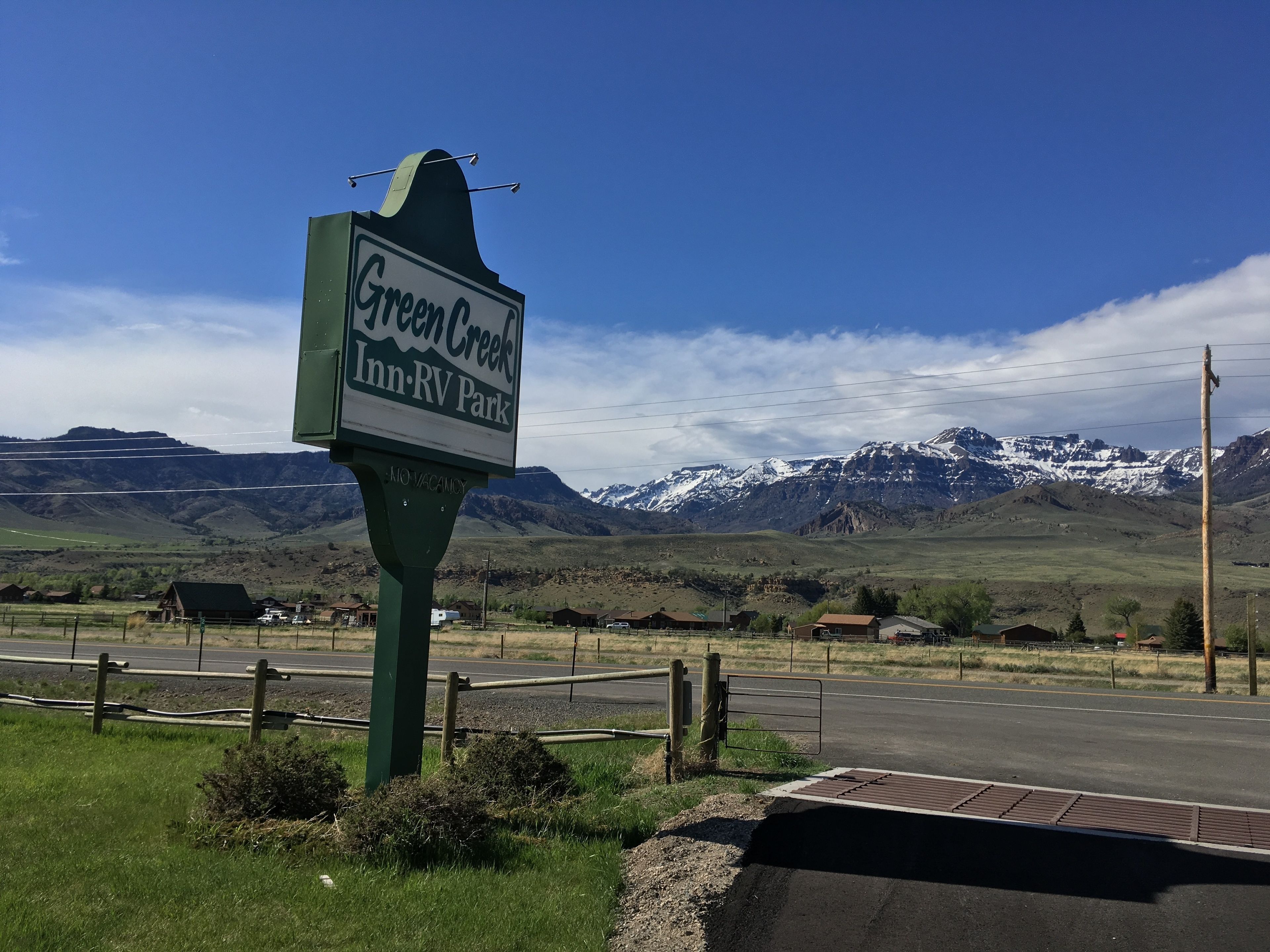 A sign for Green Creek Inn-RV Park with a mountainous backdrop.