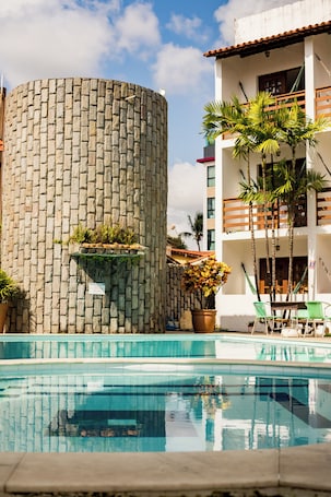 Una piscina al aire libre, sombrillas, sillones reclinables de piscina