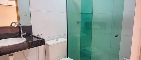 A bathroom with a white toilet, a sink, and a glass shower enclosure.