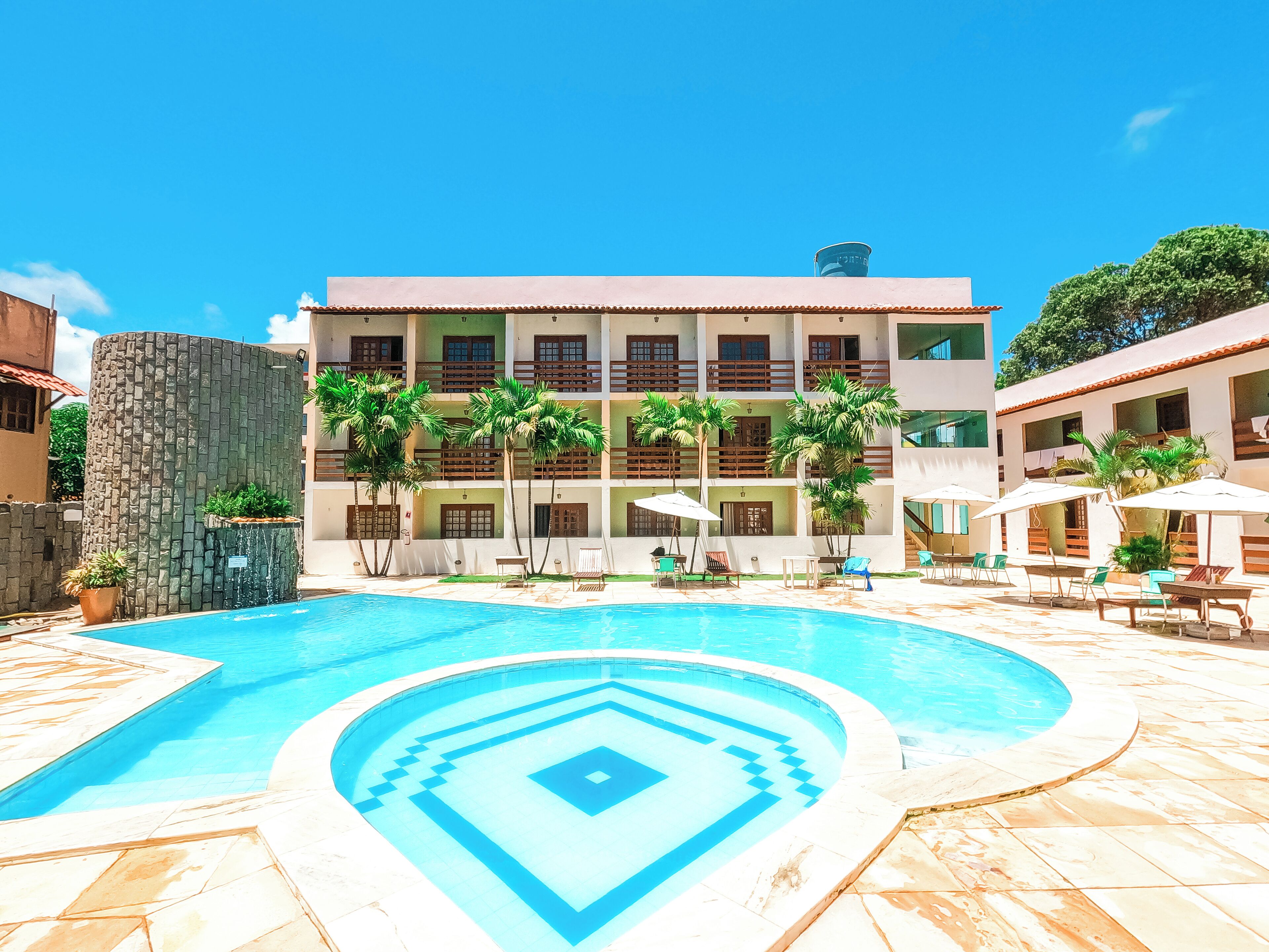 A hotel with a swimming pool, multiple balconies, and outdoor seating areas.