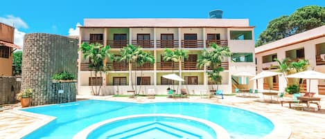 A hotel with a swimming pool, multiple balconies, and outdoor seating areas.