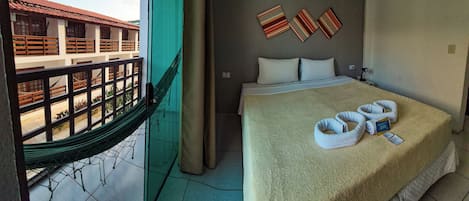 Una habitación de hotel con una cama, una hamaca y vista al exterior del edificio.