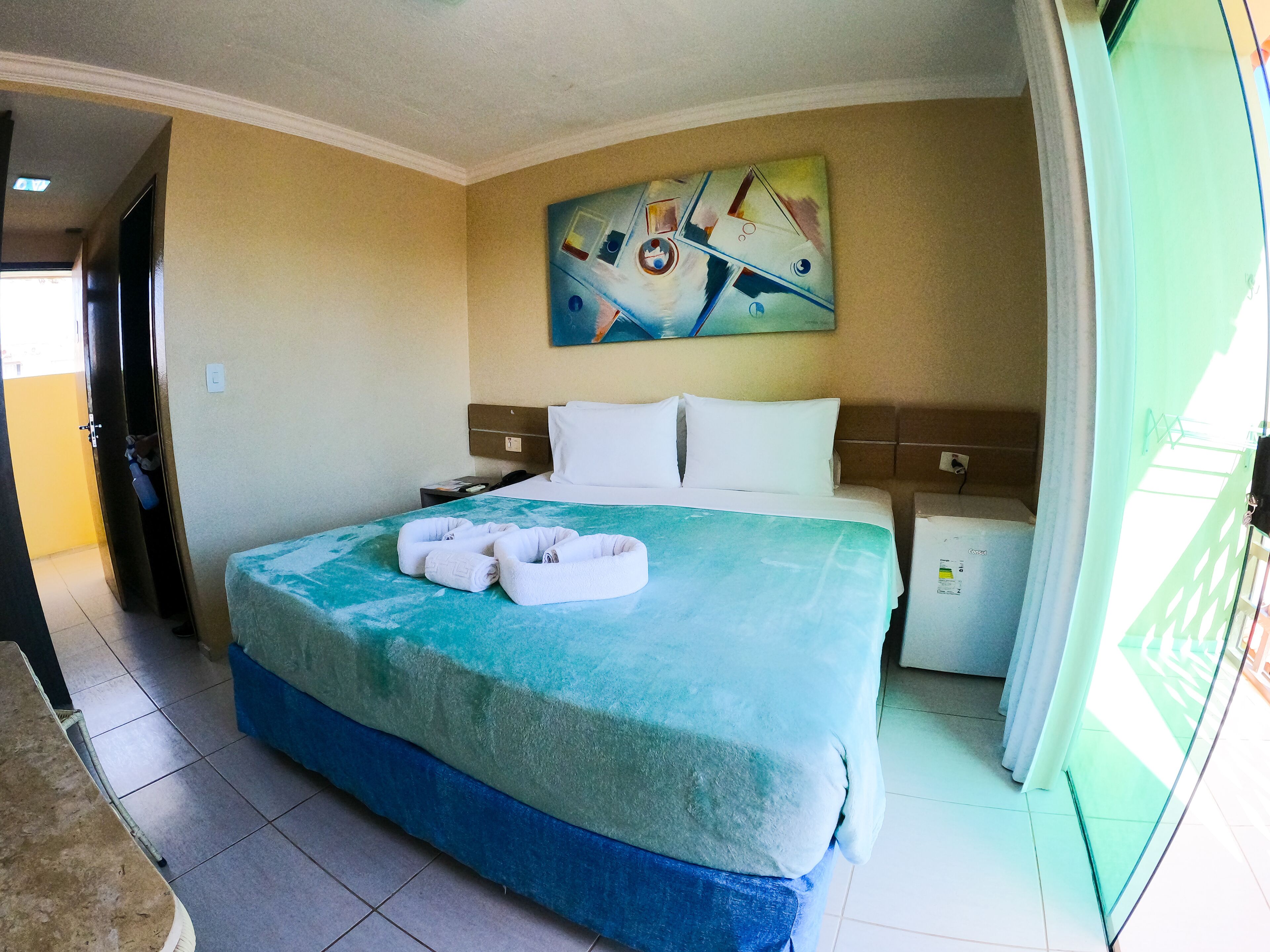 Een hotelkamer met een bed, een schilderij aan de muur en een bureau met een stoel.