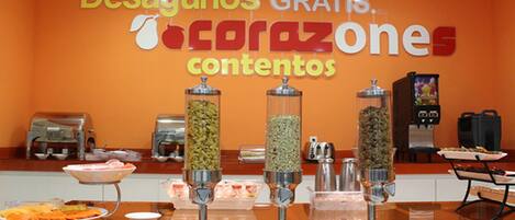 A buffet area with a sign reading "Desayunos Gratis. Tocrazones contenidos" and various food dispensers.