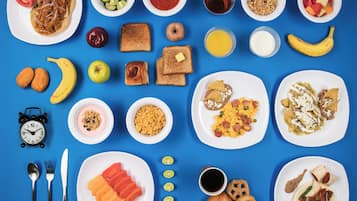A variety of breakfast foods and snacks arranged on plates and bowls against a blue background.