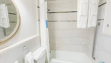 A bathroom with a white sink, toilet, and bathtub. There is a shower curtain, a towel rack, and a mirror with a gold frame.