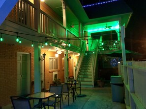 An outdoor patio area with tables and chairs, a staircase, and string lights.